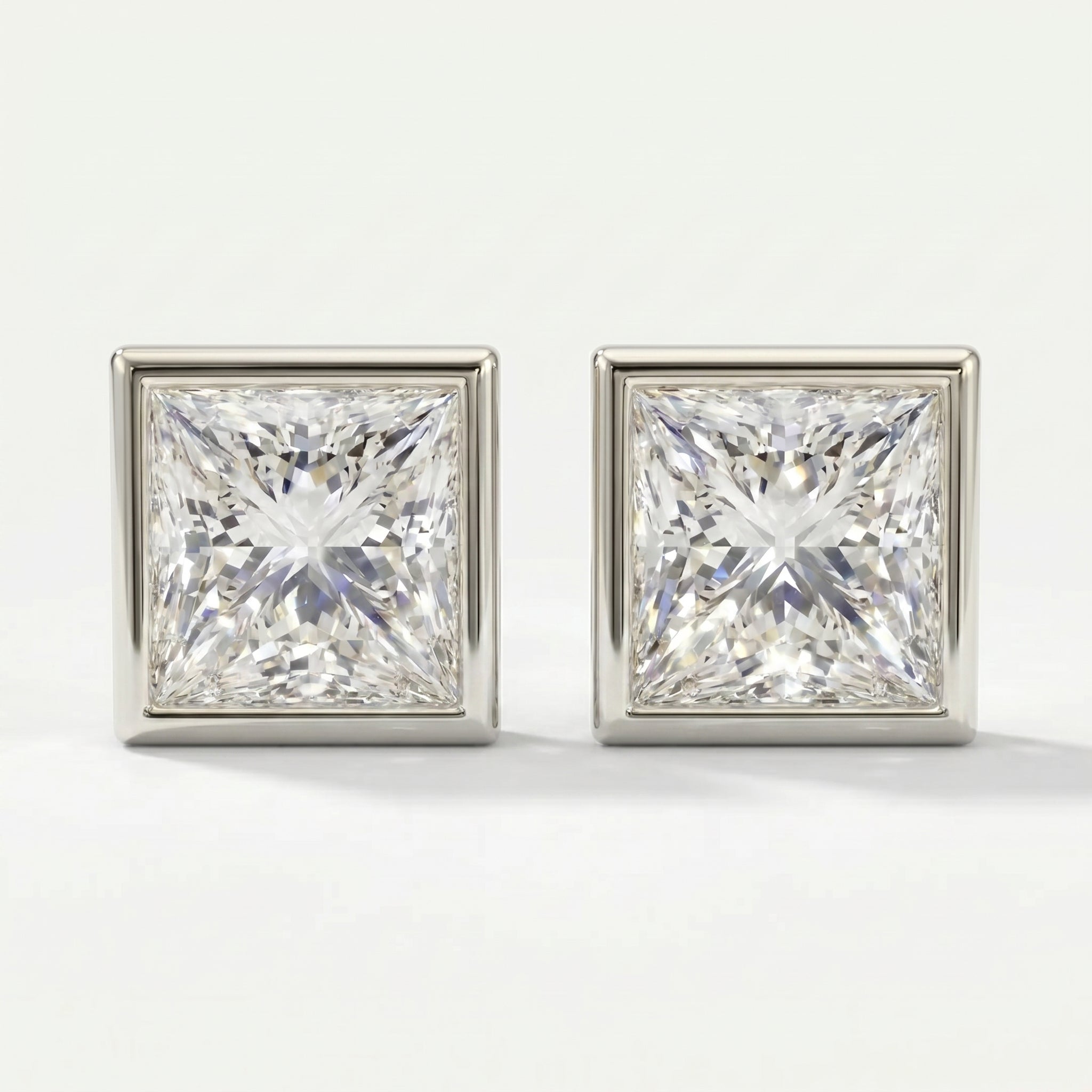 Pair of square-cut diamond earrings on a light gray background