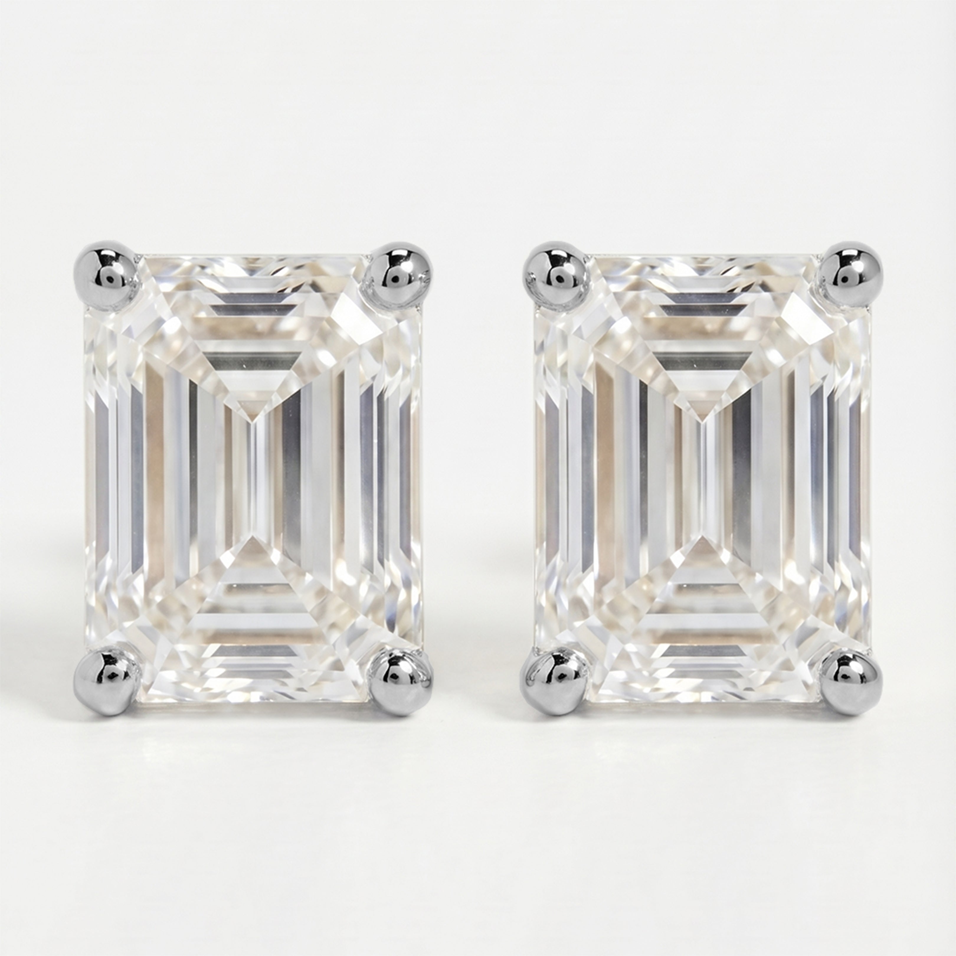Pair of emerald-cut diamond earrings on a white background