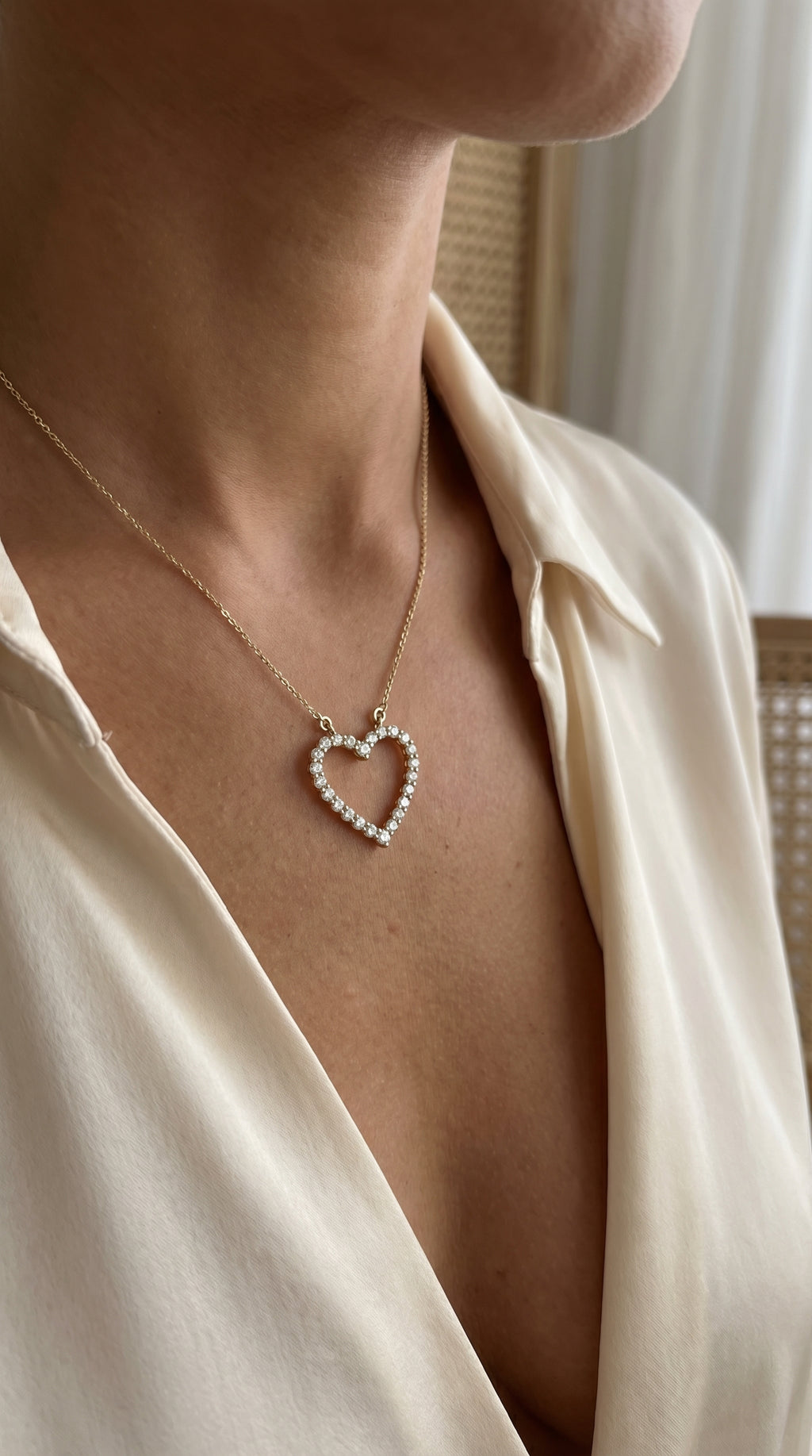 Necklace with a heart-shaped pendant worn by a person in a beige shirt.