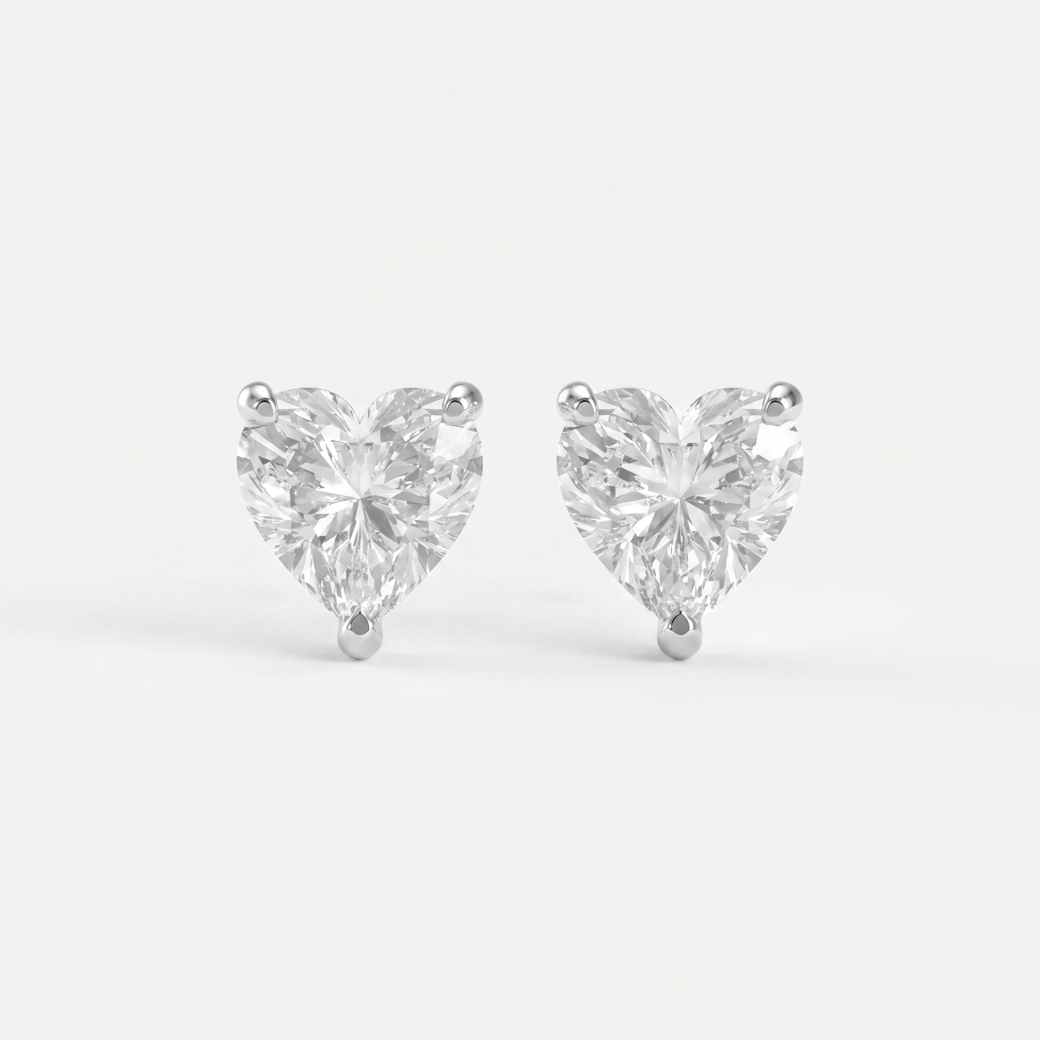 Heart-shaped diamond earrings on a light gray background
