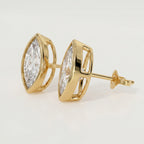 Gold earrings with clear gemstones on a light gray background