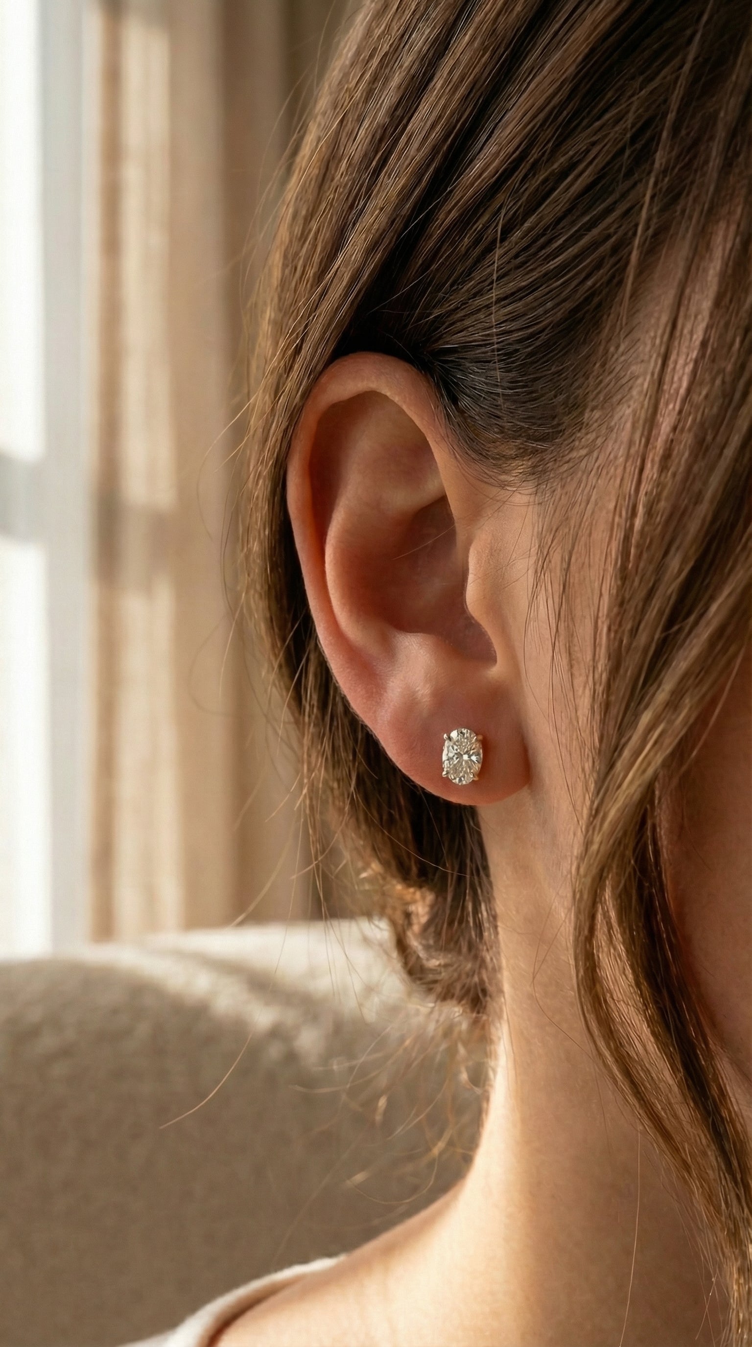 Close-up of an ear wearing a diamond earring with a blurred background