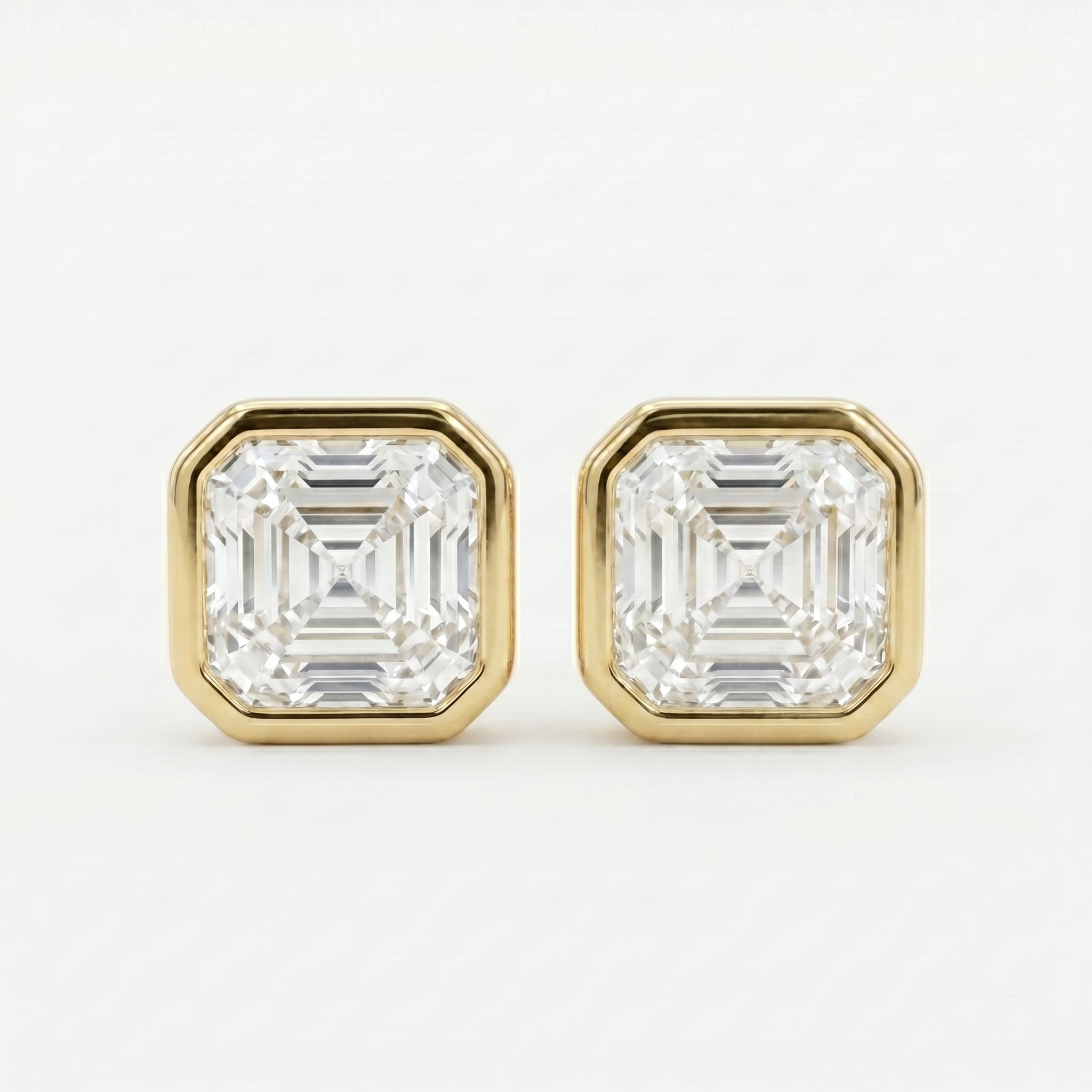 Gold earrings with Asscher-cut gemstones on a white background