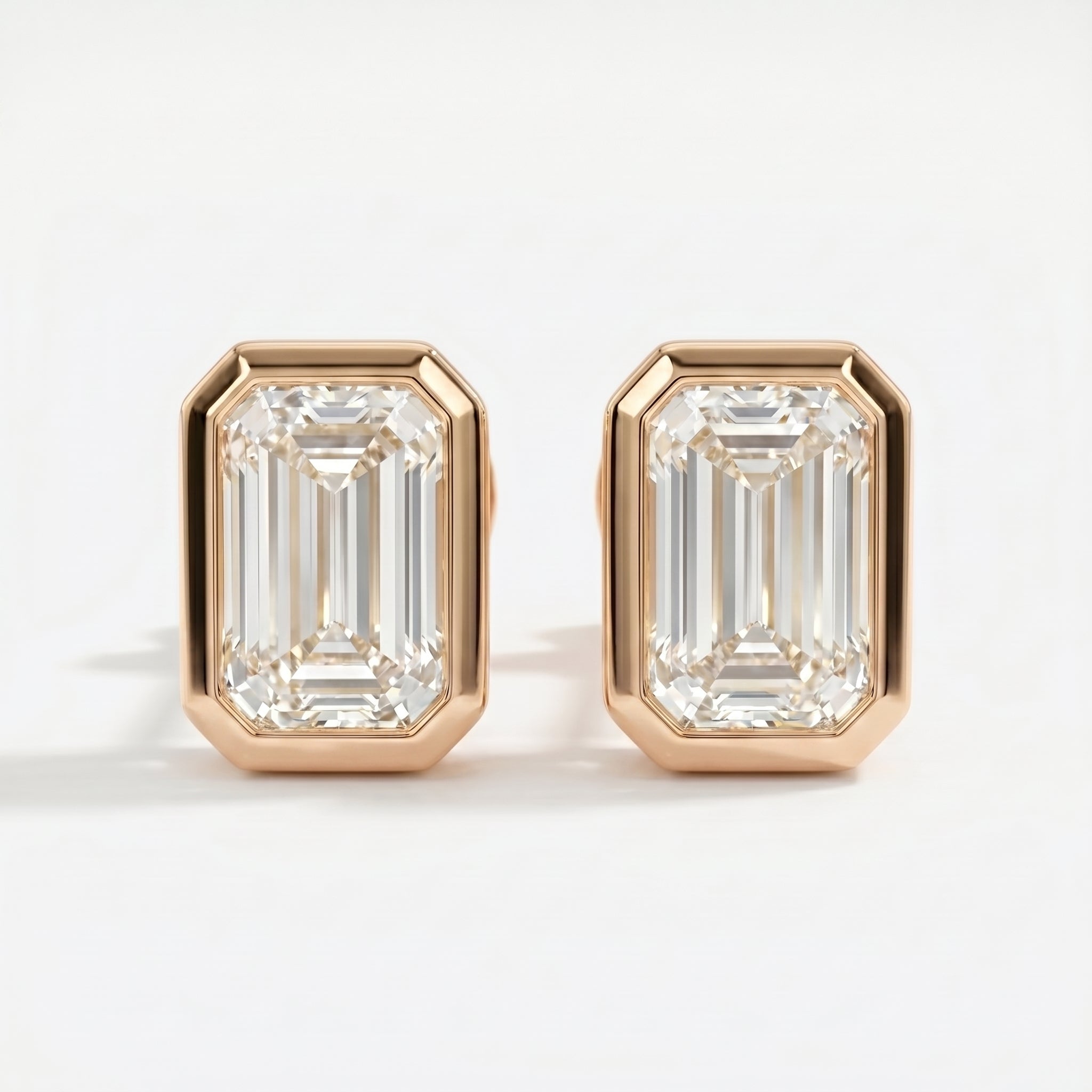 Pair of diamond earrings with rose gold setting on a white background