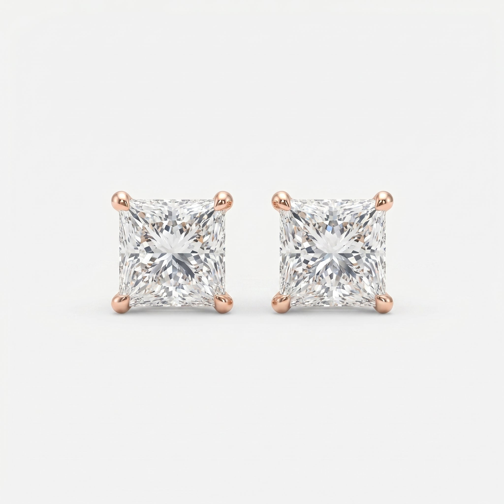 Pair of diamond stud earrings with rose gold prongs on a light gray background