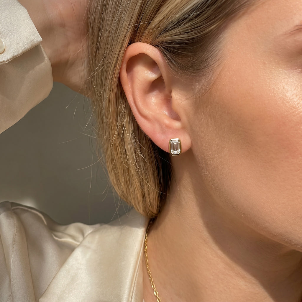 Close-up of a person wearing diamond earrings with a neutral background