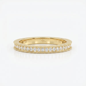 Yellow gold diamond eternity band with round brilliant diamonds and milgrain detailing on a clean white background