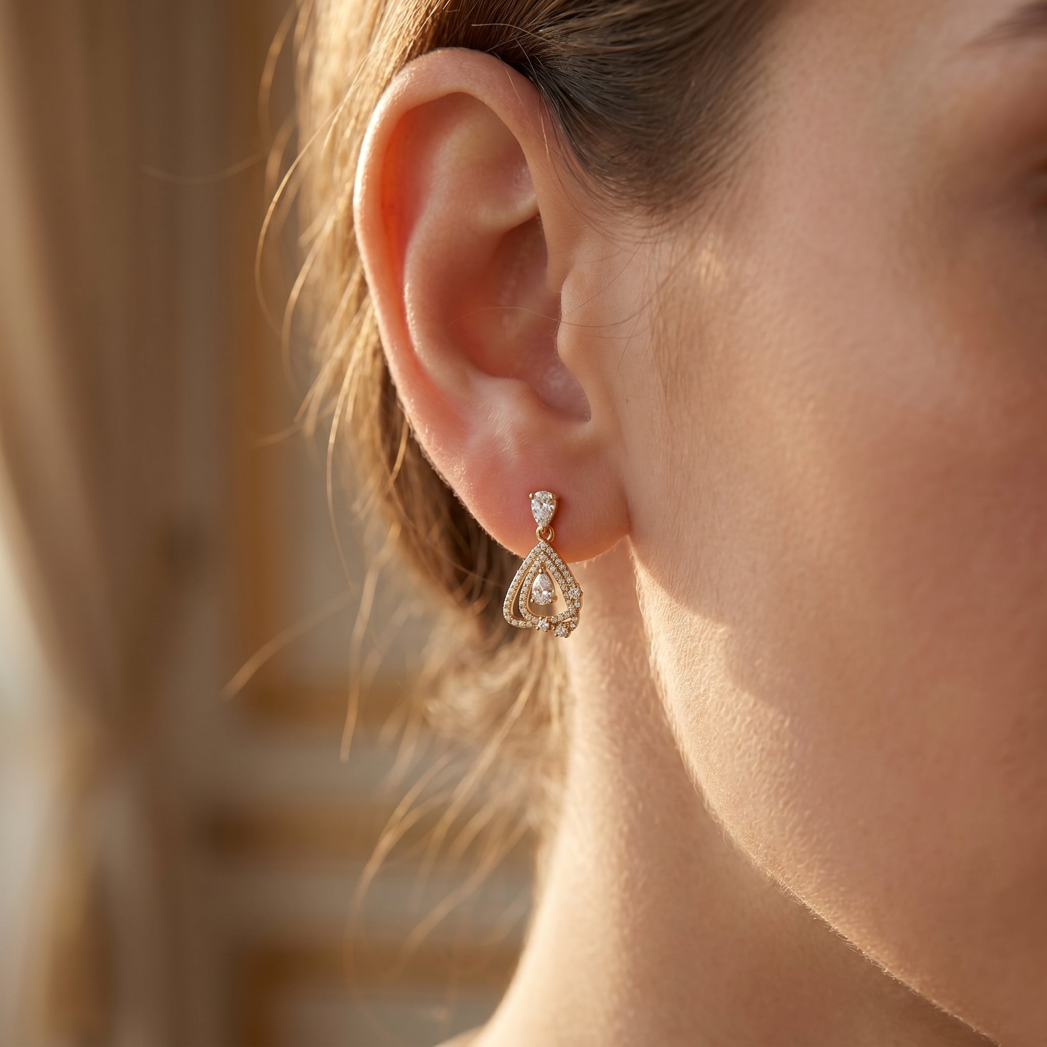 Close-up of pavé stone detailing and pear-cut gemstone in Yellow gold luxury drop earrings.