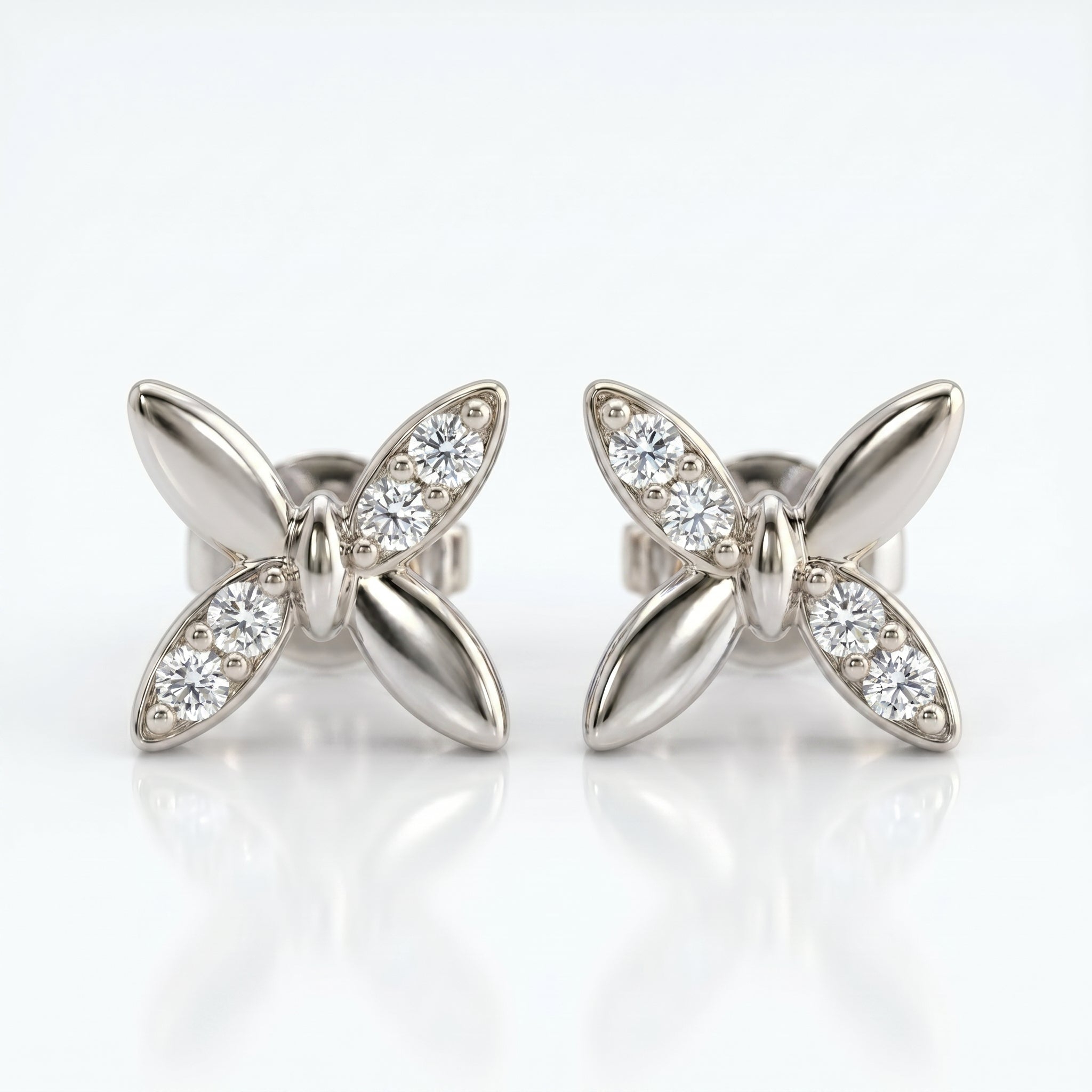 White gold butterfly diamond stud earrings with pavé stones in a minimalist luxury jewelry studio setting
