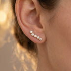 Side profile of bezel-set diamond crawler earrings showing polished gold setting craftsmanship