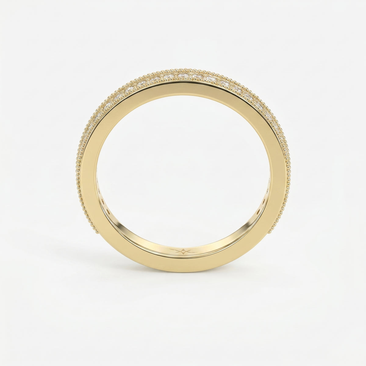 Diamond eternity band in yellow gold featuring round brilliant diamonds and milgrain detailing on a white background.