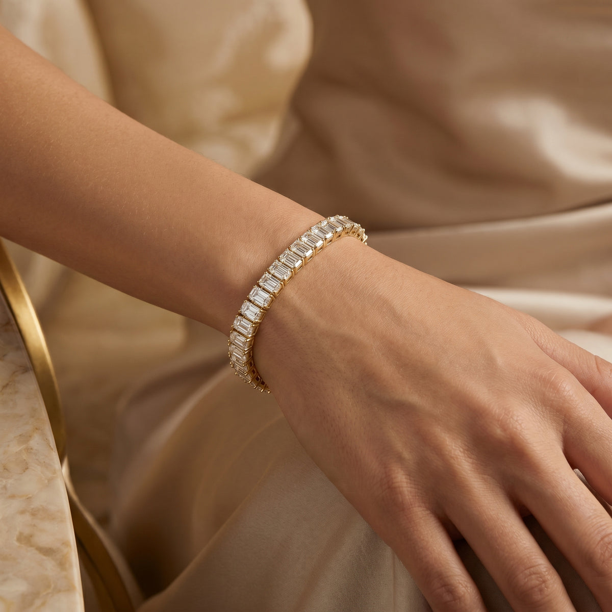 Emerald cut diamond tennis bracelet in gold setting featuring continuous sparkling stones and secure clasp design