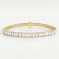 Emerald cut diamond tennis bracelet in yellow gold with secure box clasp and brilliant sparkle on white background.