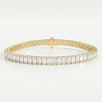 Emerald cut diamond tennis bracelet in yellow gold with secure box clasp and brilliant sparkle on white background.