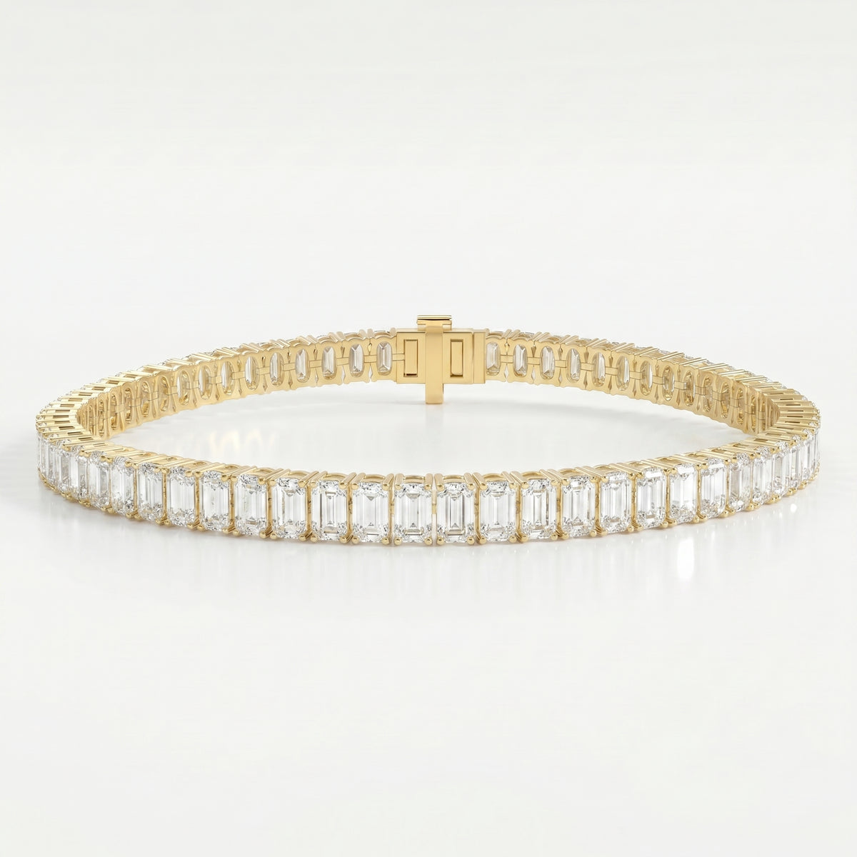 Emerald cut diamond tennis bracelet in yellow gold with secure box clasp and brilliant sparkle on white background.