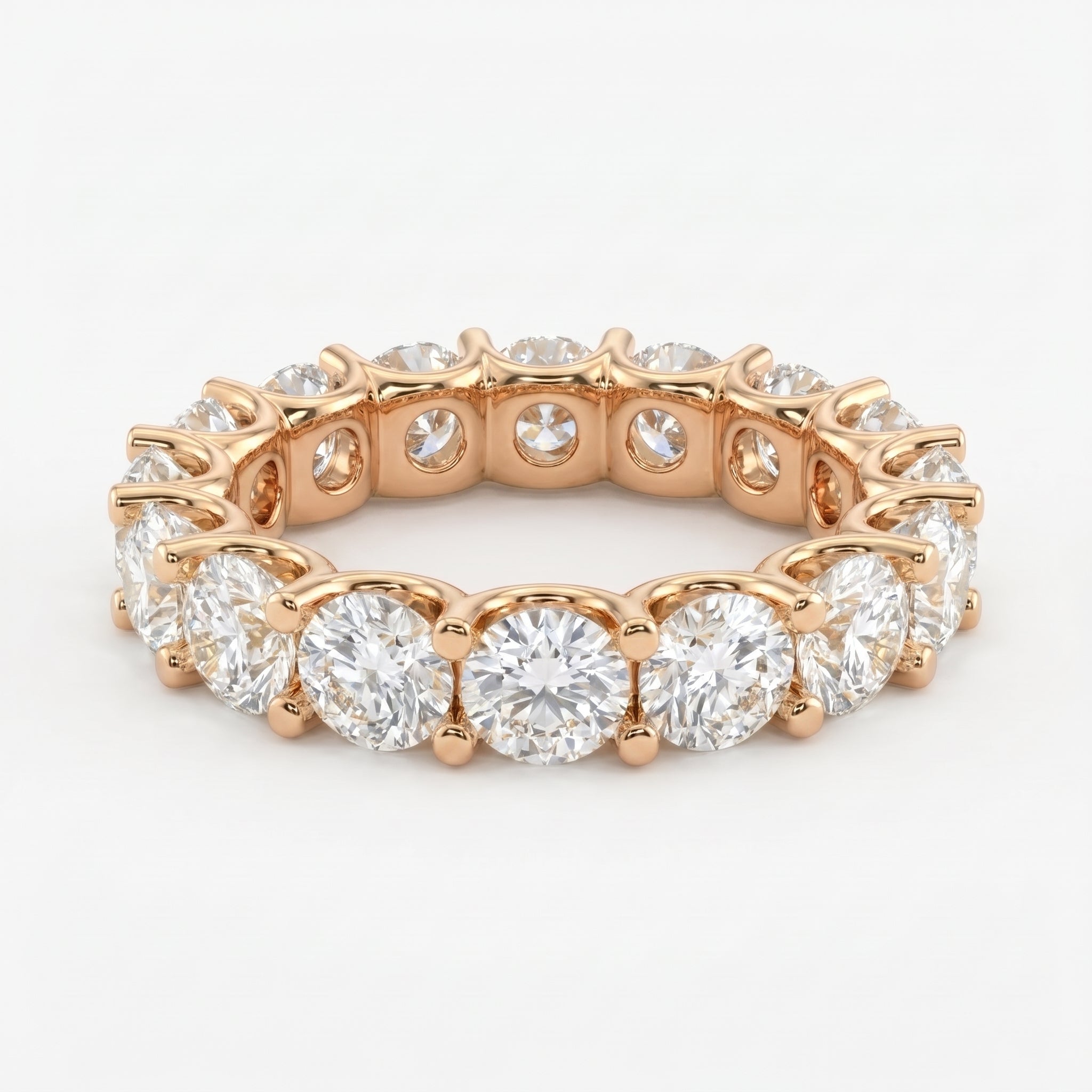 Rose gold round brilliant diamond eternity ring with shared prong setting on a white background for luxury jewelry shopping.