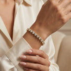 Heart-cut diamond tennis bracelet in yellow gold worn on wrist featuring sparkling stones and secure clasp design.