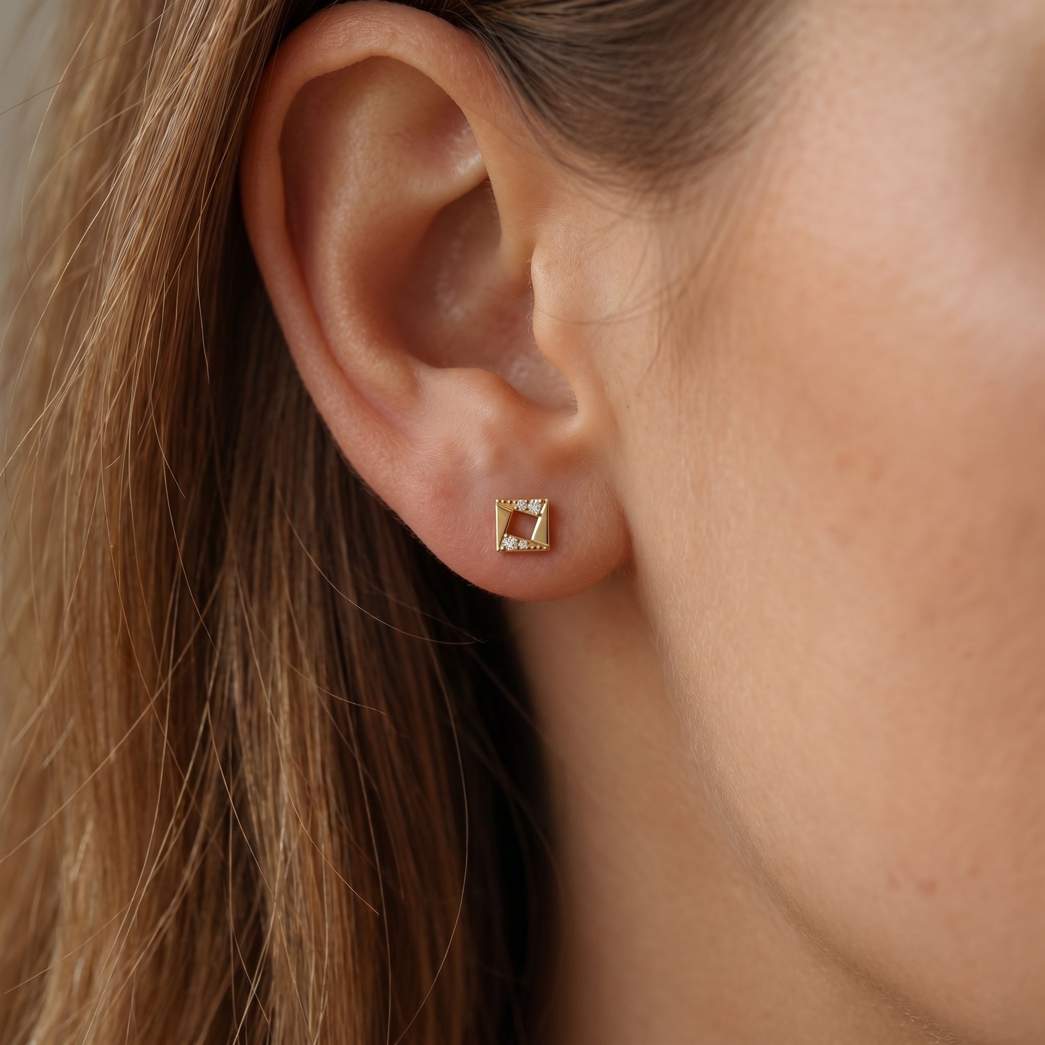 Side profile of geometric diamond stud earrings showing polished rose gold craftsmanship and secure backing