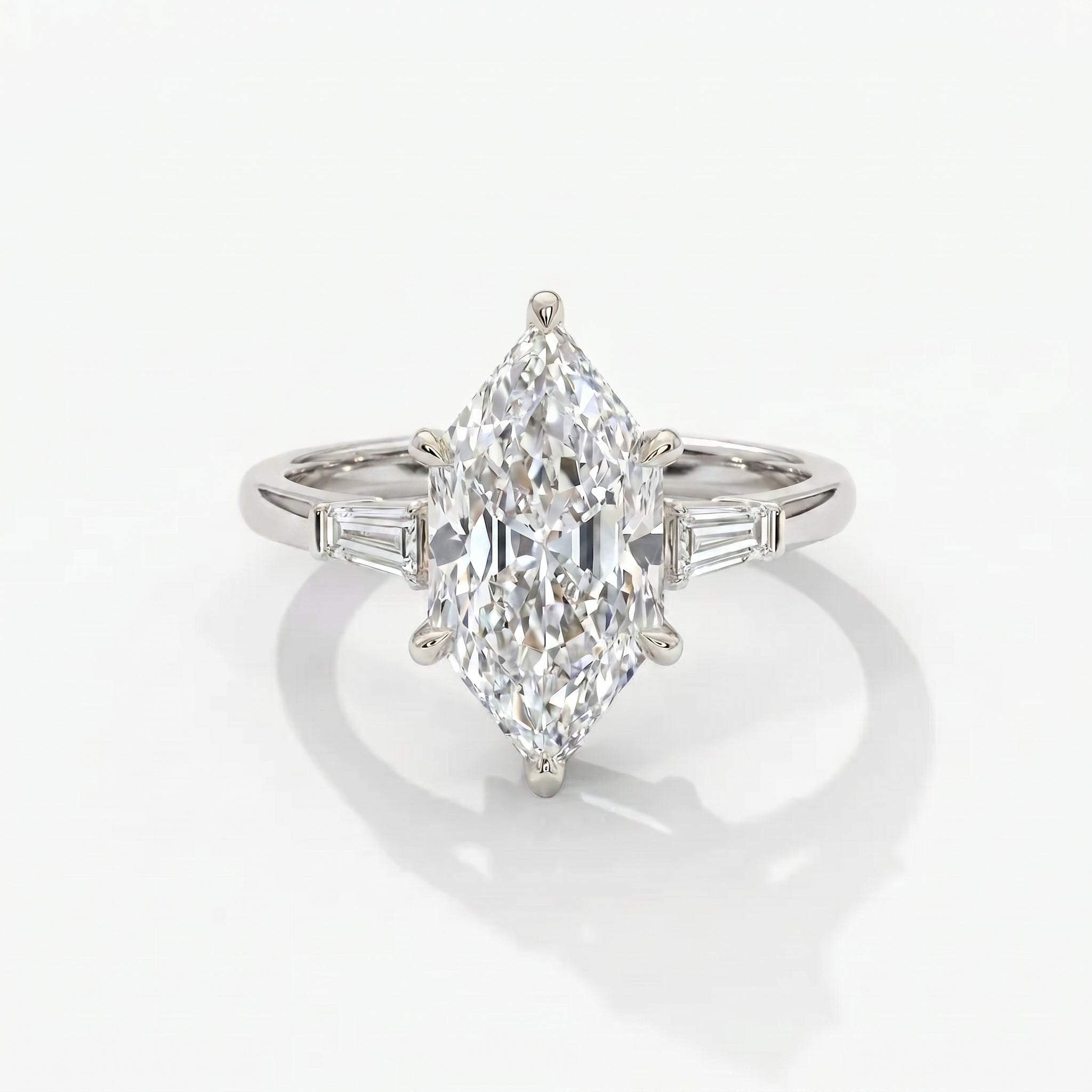 Luxury marquise cut diamond engagement ring with tapered baguette side stones in White gold setting on white background