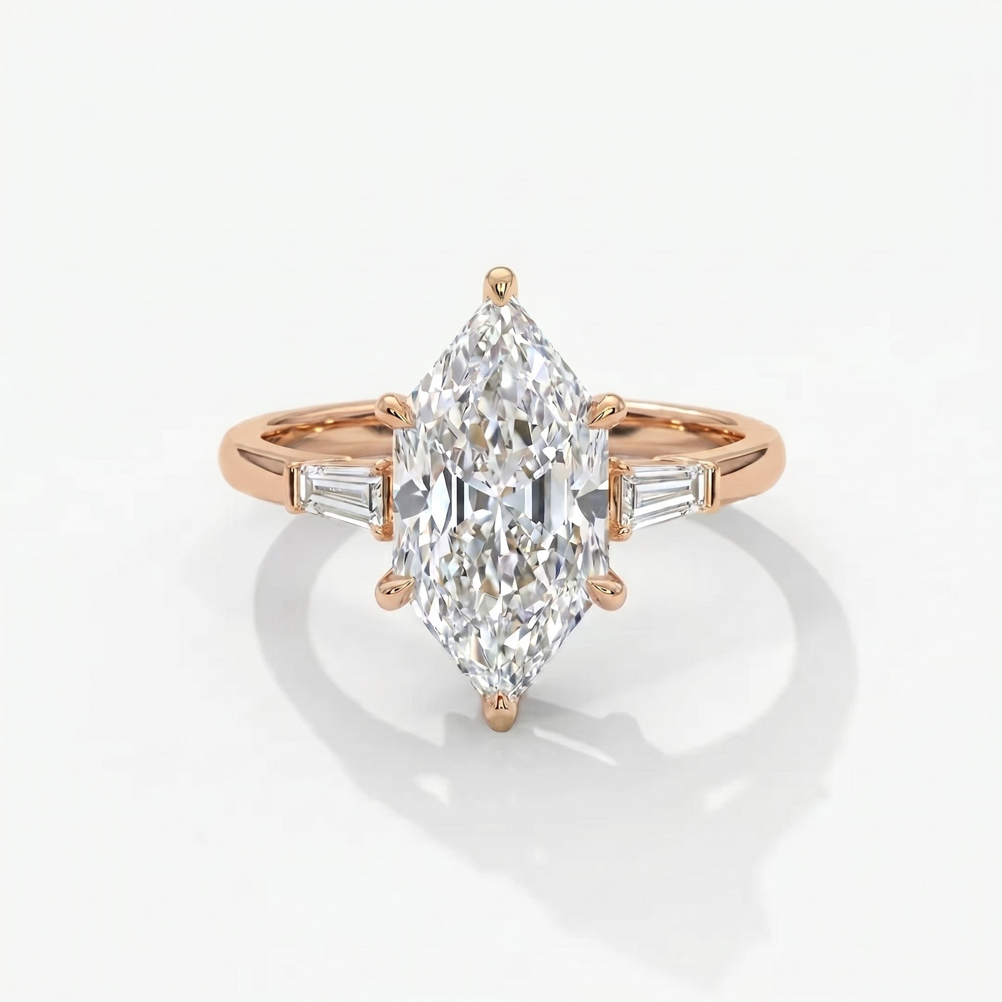 Marquise diamond engagement ring with tapered baguette side stones in polished rose gold setting on white background