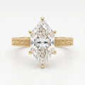 Yellow gold marquise cut diamond engagement ring with detailed milgrain engraving and elegant solitaire design.