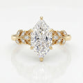 Marquise diamond engagement ring in yellow gold with leaf-inspired diamond accents on a clean white background