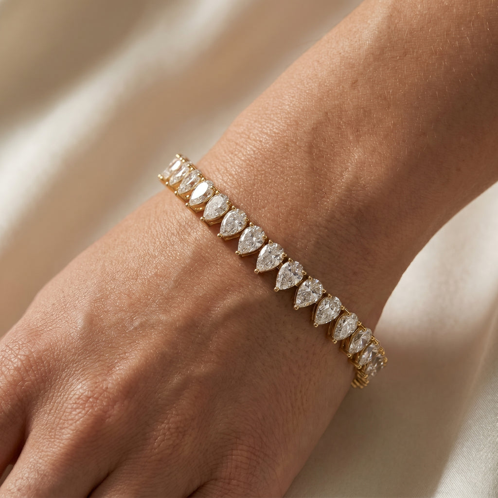Pear cut diamond tennis bracelet in yellow gold with continuous sparkling stones and secure box clasp