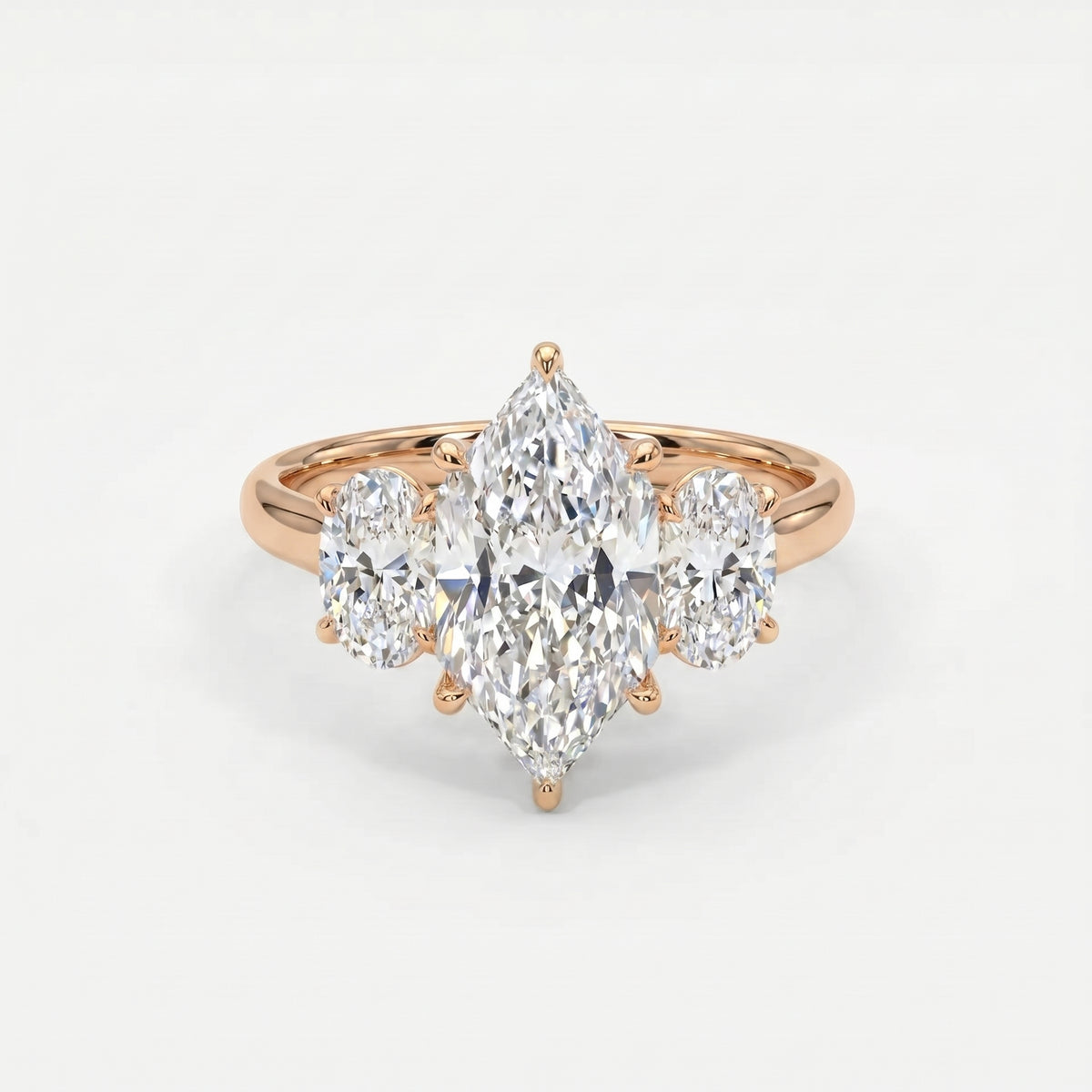 Rose gold marquise cut three stone engagement ring with oval side diamonds and polished luxury bridal setting