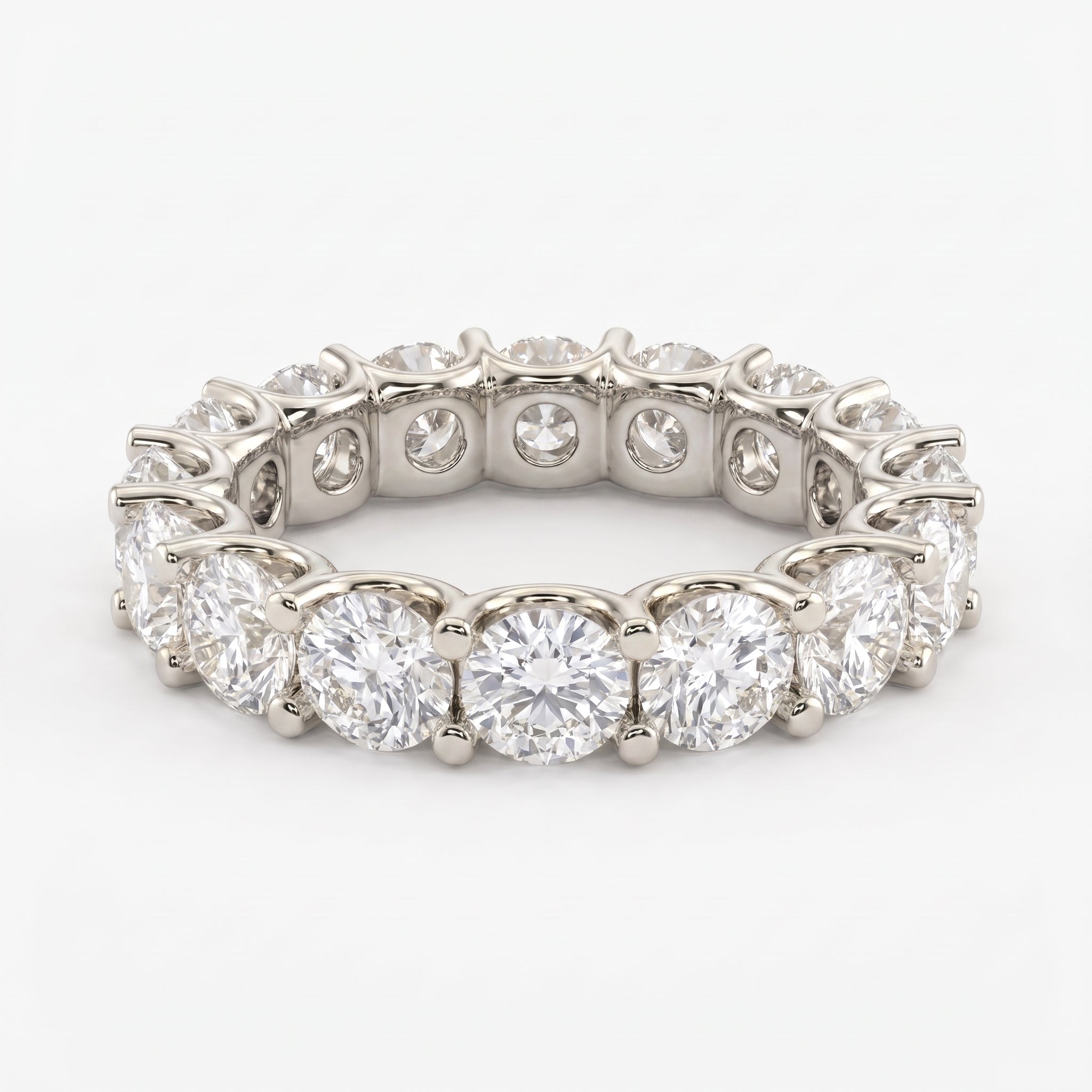 Round brilliant diamond eternity band ring in polished white gold with shared prong setting on a clean white background.