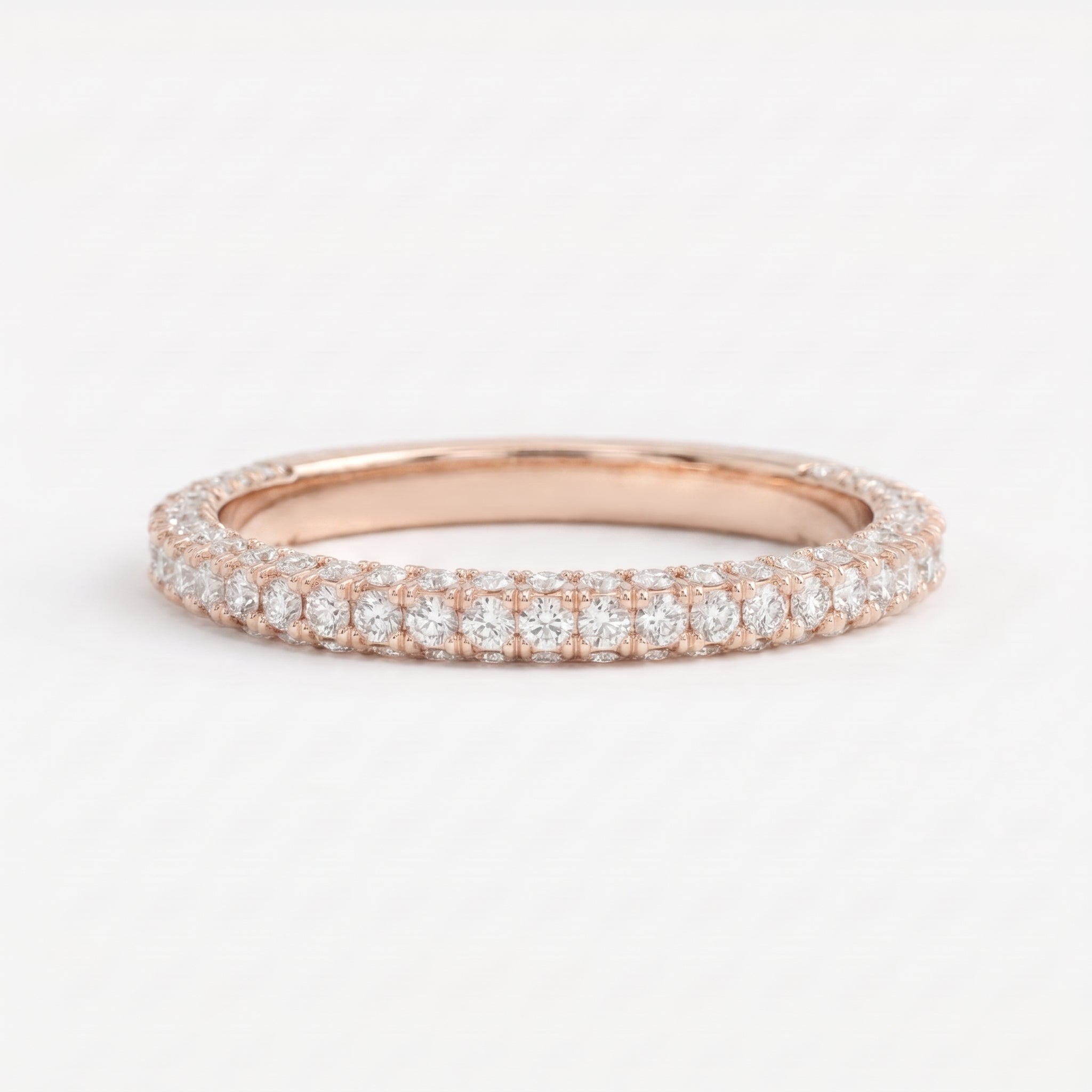Round brilliant diamond eternity wedding band in polished Rose gold with shared-prong setting, stackable fine jewelry for weddings and anniversaries.