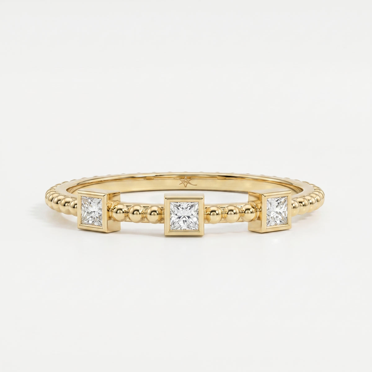 Three princess-cut diamond beaded yellow gold ring with modern bezel settings and minimalist luxury design