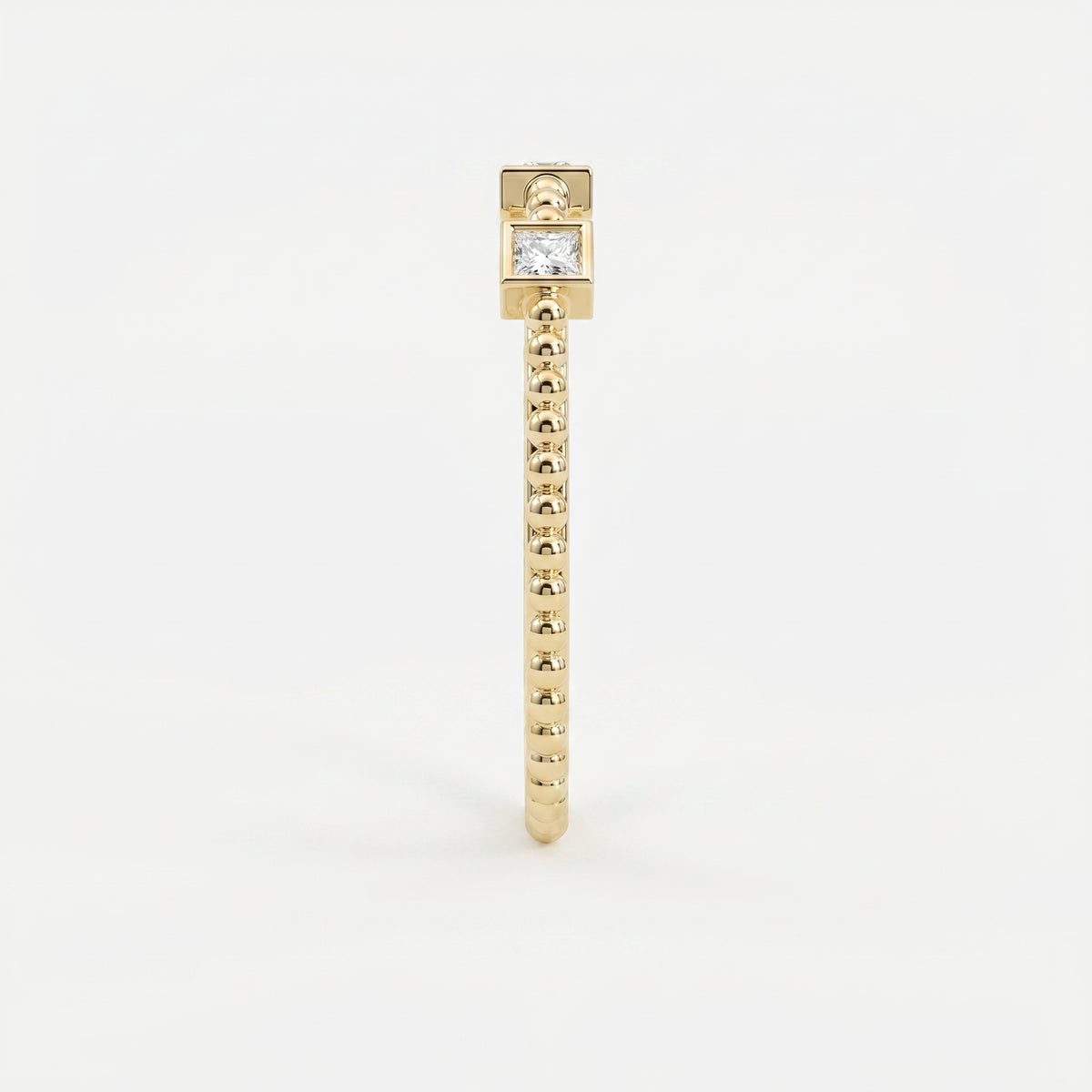 Side profile of yellow gold diamond stacking ring showing low bezel settings and beaded band detail