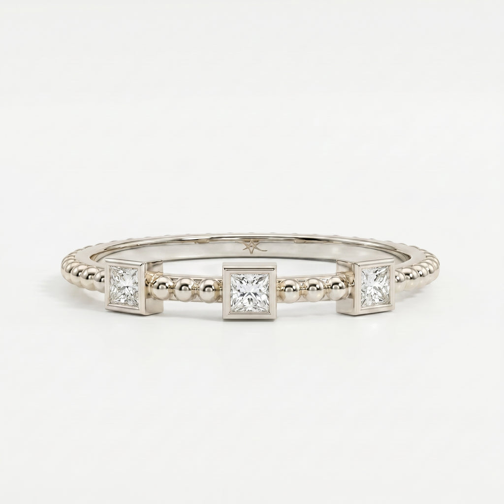 Top-down flat lay of a three-stone princess-cut diamond ring on a clean white jewelry photography background