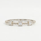 Top-down flat lay of a three-stone princess-cut diamond ring on a clean white jewelry photography background