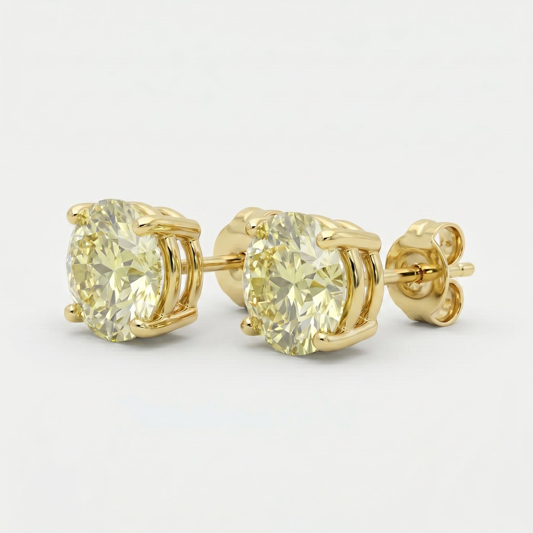 Luxury yellow diamond stud earrings in polished yellow gold with round-cut stones and four-prong basket setting