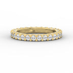 Yellow gold full eternity diamond ring with round brilliant diamonds in a shared prong setting on a pure white background.