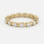 Yellow gold diamond eternity band with round brilliant diamonds in a modern shared-prong setting on white background