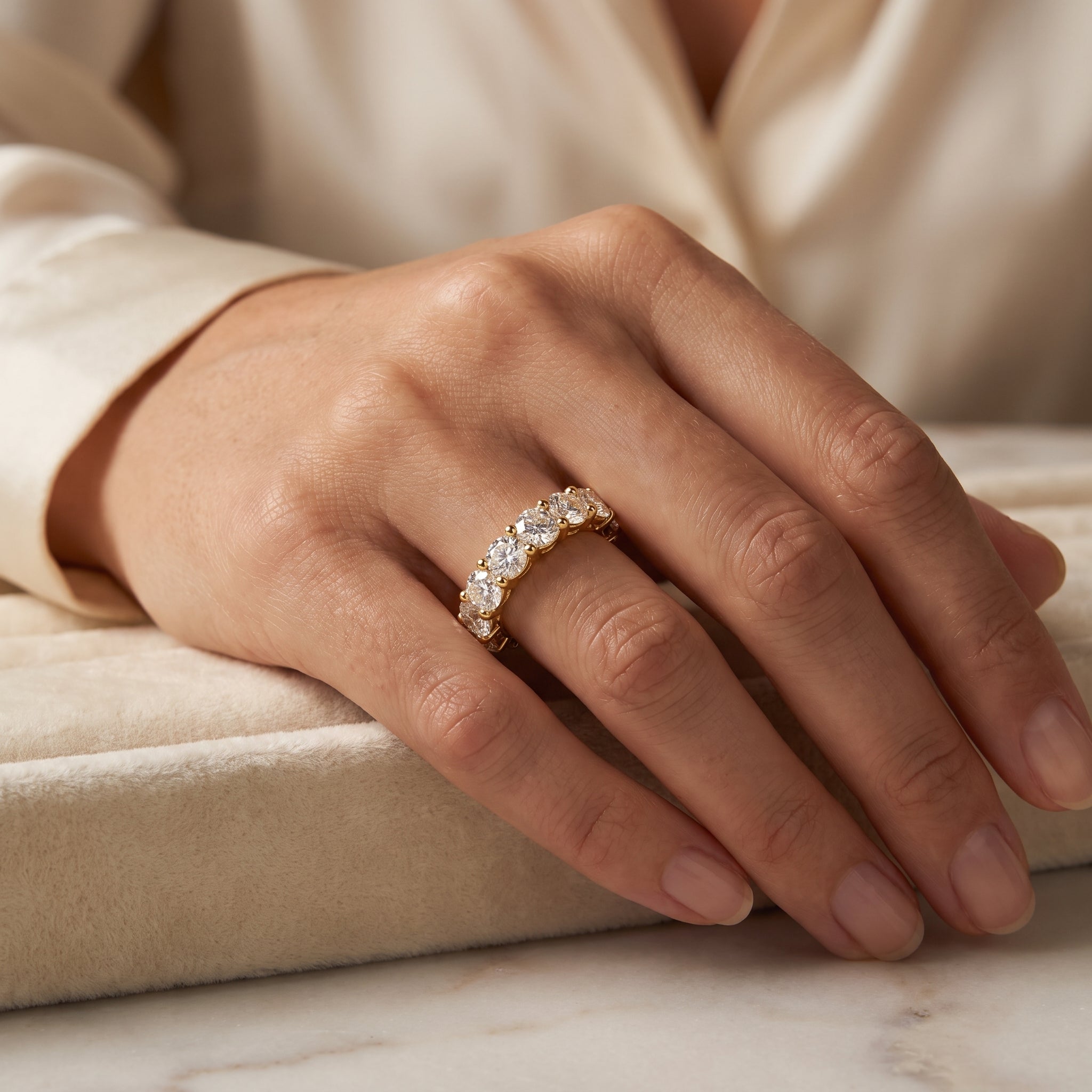 Yellow gold diamond eternity ring with round brilliant diamonds worn on hand, showcasing elegant shared prong design and luxury sparkle.