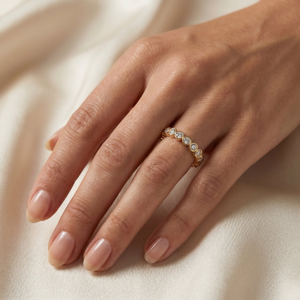 Woman wearing a yellow gold bezel-set diamond eternity ring in a luxury everyday lifestyle setting