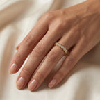 Woman wearing a yellow gold bezel-set diamond eternity ring in a luxury everyday lifestyle setting